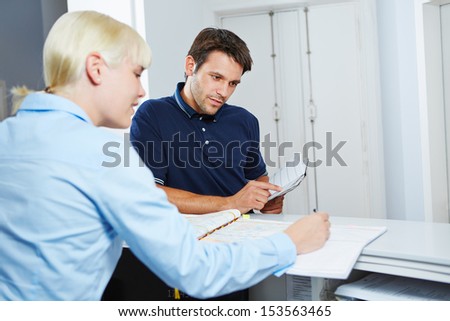 Man with appointment book scheduling an appointment at reception of dentist