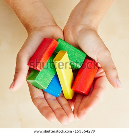 Two hands from above holding colorful building bricks