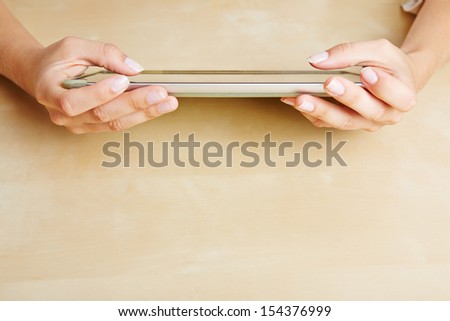 Two hands of a woman using a tablet PC on a table