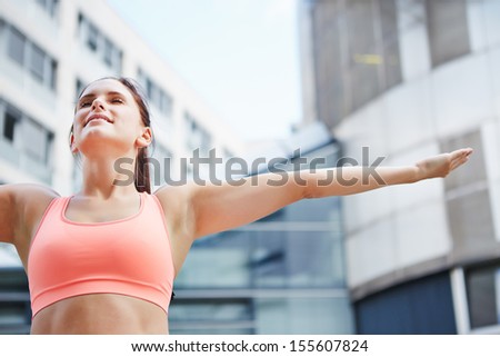 Sporty woman doing breathing exercise for relaxation in the city