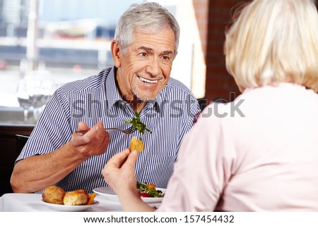 Happy senior couple eating in restaurant for lunch