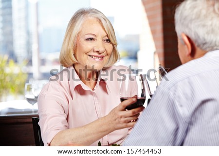 Happy senior woman drinking a glass of red wine with her husband in a restaurant