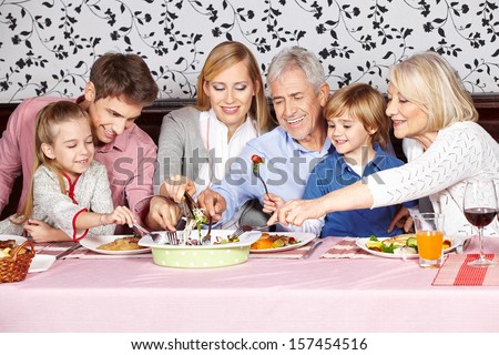 Hungry family reaching for food at dinner table at the same time