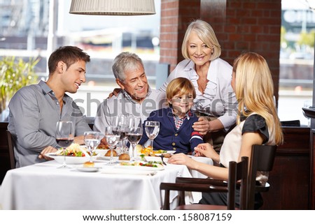 Happy Family Sitting In A Restaurant And Eating Out