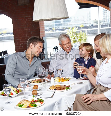 Happy Family With Two Children And Grandparents Eating In A Restaurant