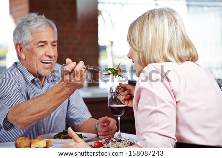 Man in restaurant letting his woman taste from his food