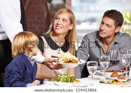 Waiter Serving A Family In A Restaurant And Bringing A Full Plate