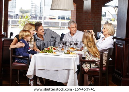 Happy family taking pictures with camera in a restaurant