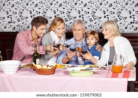 Happy family at dinner table clinking glasses of red wine
