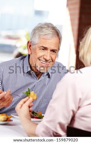 Elderly happy man talking to woman in a restaurant
