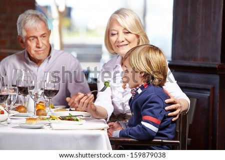Child eating out with his grandparents in a restaurant