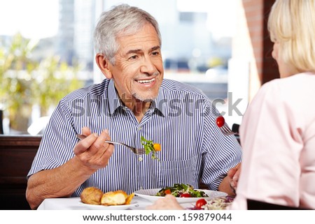 Senior Man Talking To Woman While Eating In A Restaurant
