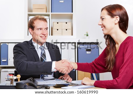 Smiling woman shaking hands with financial consultant in the office