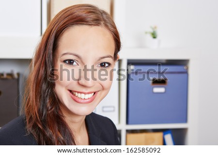 Face of a young happy smiling business woman in her office