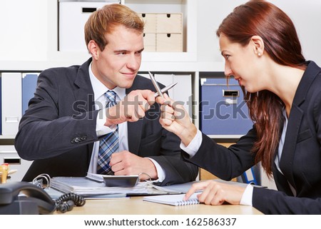 Two rivaling business people fighting with pens in the office