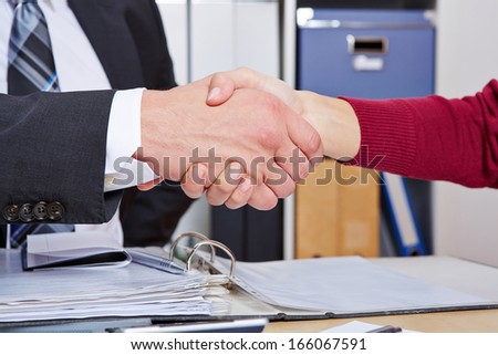 Woman making handshake with business man at desk in the office