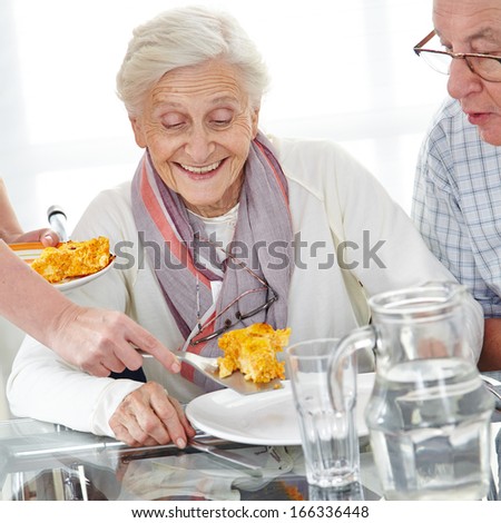 Happy senior citizen couple eating lunch in nursing home