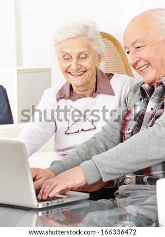 Happy senior couple chatting over internet with laptop computer