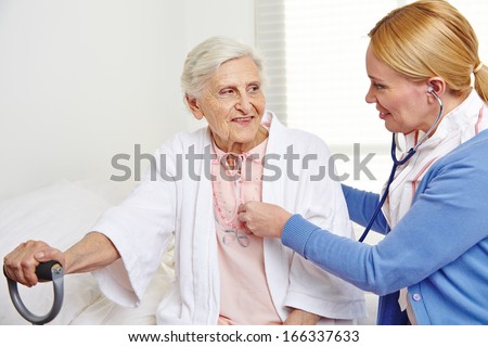 Geriatric nurse ausculting senior citizen woman in nursing home