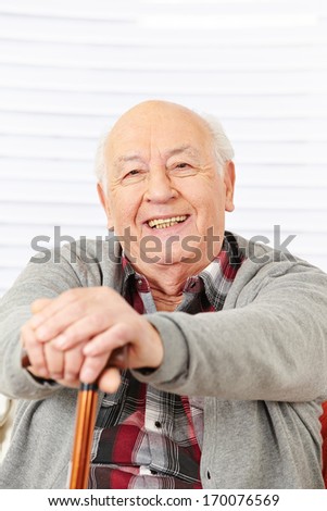 Happy senior citizen man smiling with cane in his hands