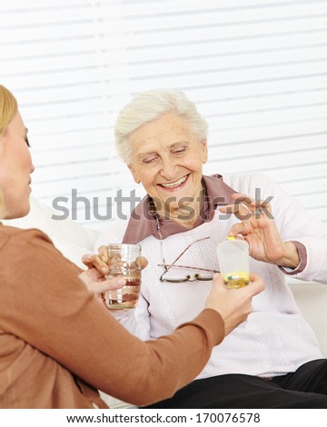 Senior woman in nursing home taking medical pills with water