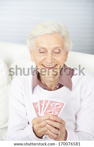 Old woman playing poker with four cards on her hand