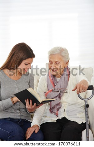 Young woman in community service reading books to senior citizens