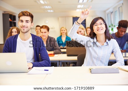 Asian student raising her hand in a university classroom