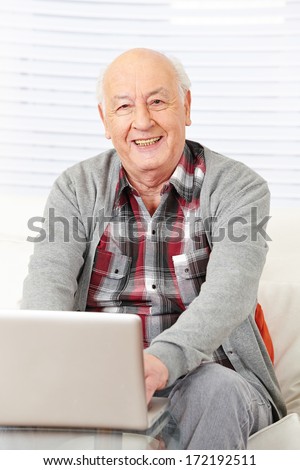 Happy senior citizen man working with laptop computer in the internet