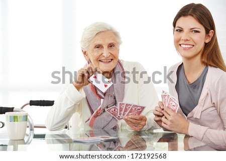 Young eldercare nurse playing cards with happy senior woman Young eldercare nurse playing cards with happy senior woman