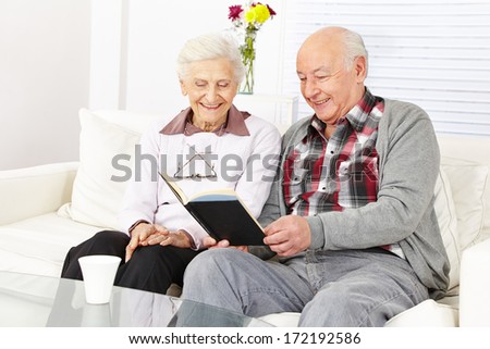 Senior citizen couple reading a book together at home