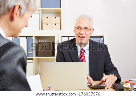 Consultant in bank at desk calculating finances with a calculator