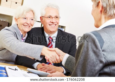 Happy elderly couple shaking hands with legal consultant in law firm