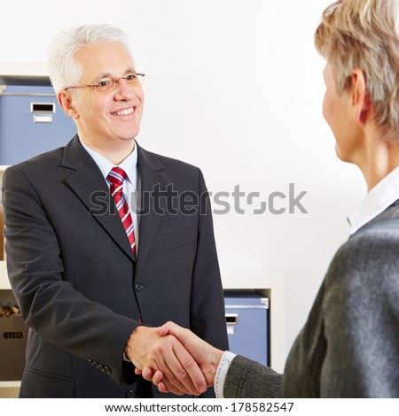 Two elderly business people shaking their hands at a job interview