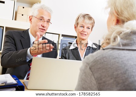 Two financial consultants talking to a senior woman in a bank