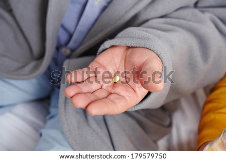 Medical pill on the wrinkly hand of an old man