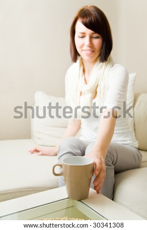 Young woman reaching for a coffee mug