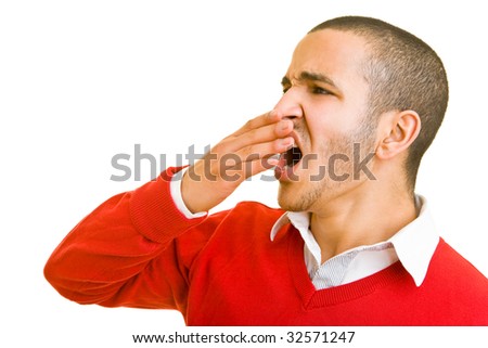 Young man is yawning and holding his hand in front of his mouth