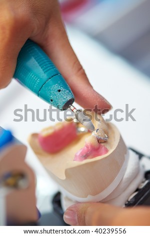 Dental technician grinding a lower jaw in a lab