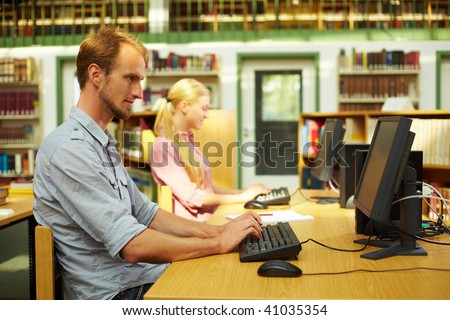 Students sitting in library and using computers
