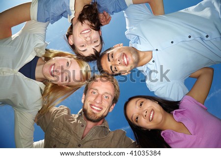 Five happy friends embracing under blue sky