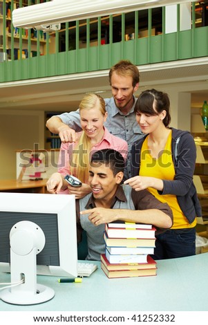 Library staff pointing at monitor on counter