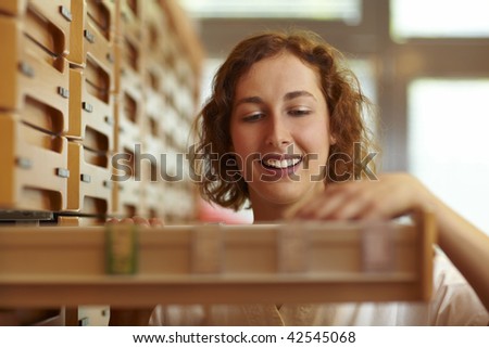 Pharmacist reaching for drawer at medicine cabinet