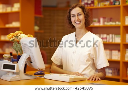 Happy pharmacist standing behind counter in pharmacy