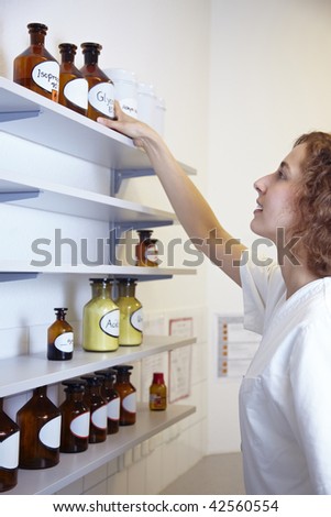 Pharmacist in lab reaching for bottle with alcohol
