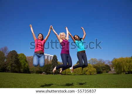 Three happy young woman jumping in a park