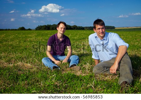 Two men sitting relaxed in a meadow