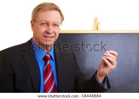 Happy teacher standing in front of a black chalkboard