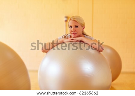 Happy woman in a gym with many gym balls