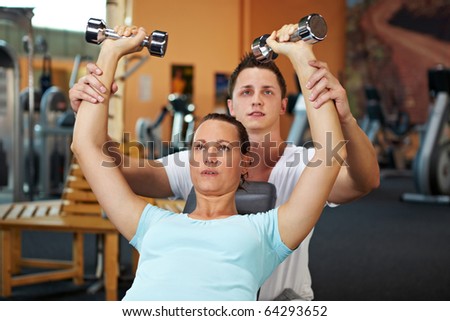 Woman doing weight training with fitness coach